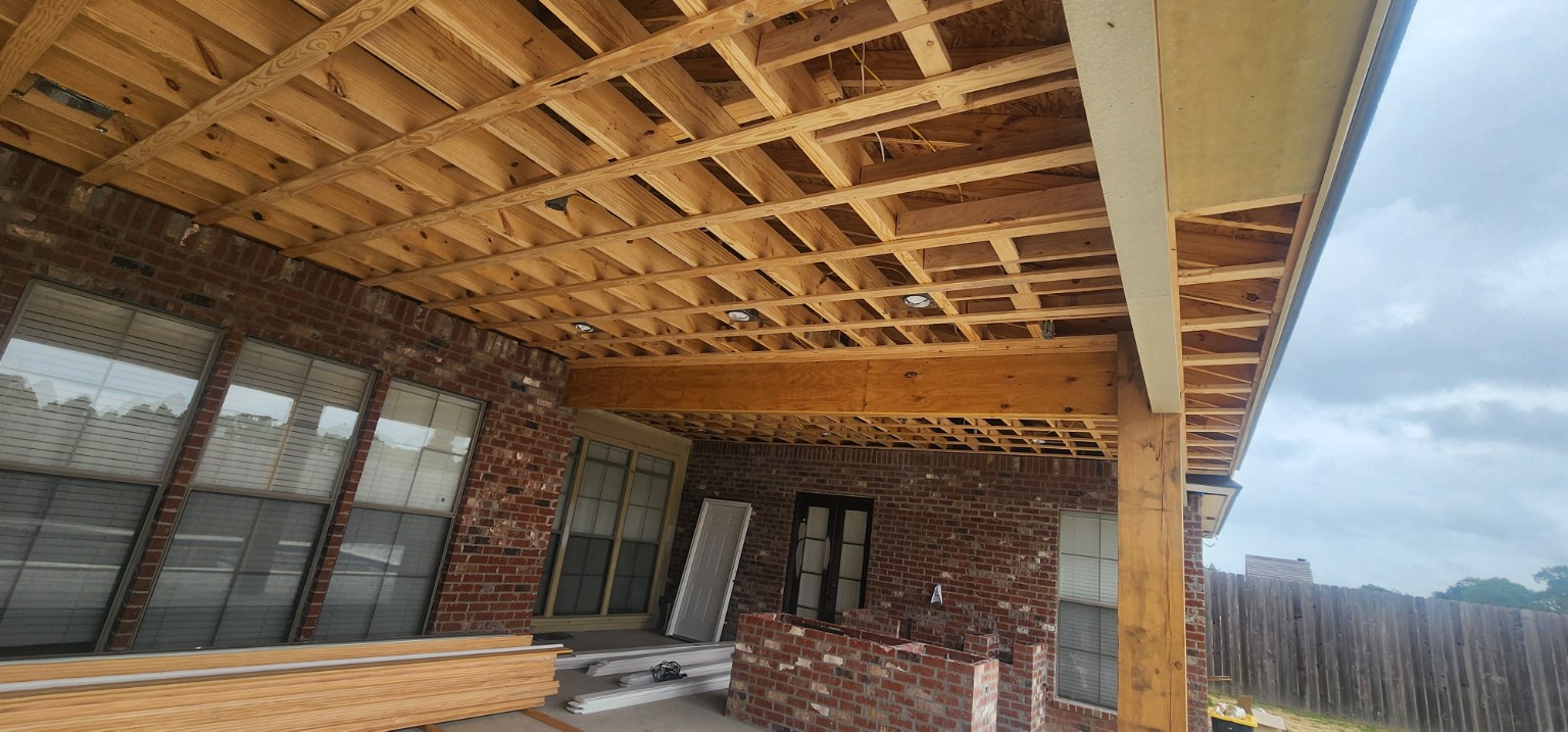 Covered patio under construction with recessed lighting installed in exposed ceiling framing