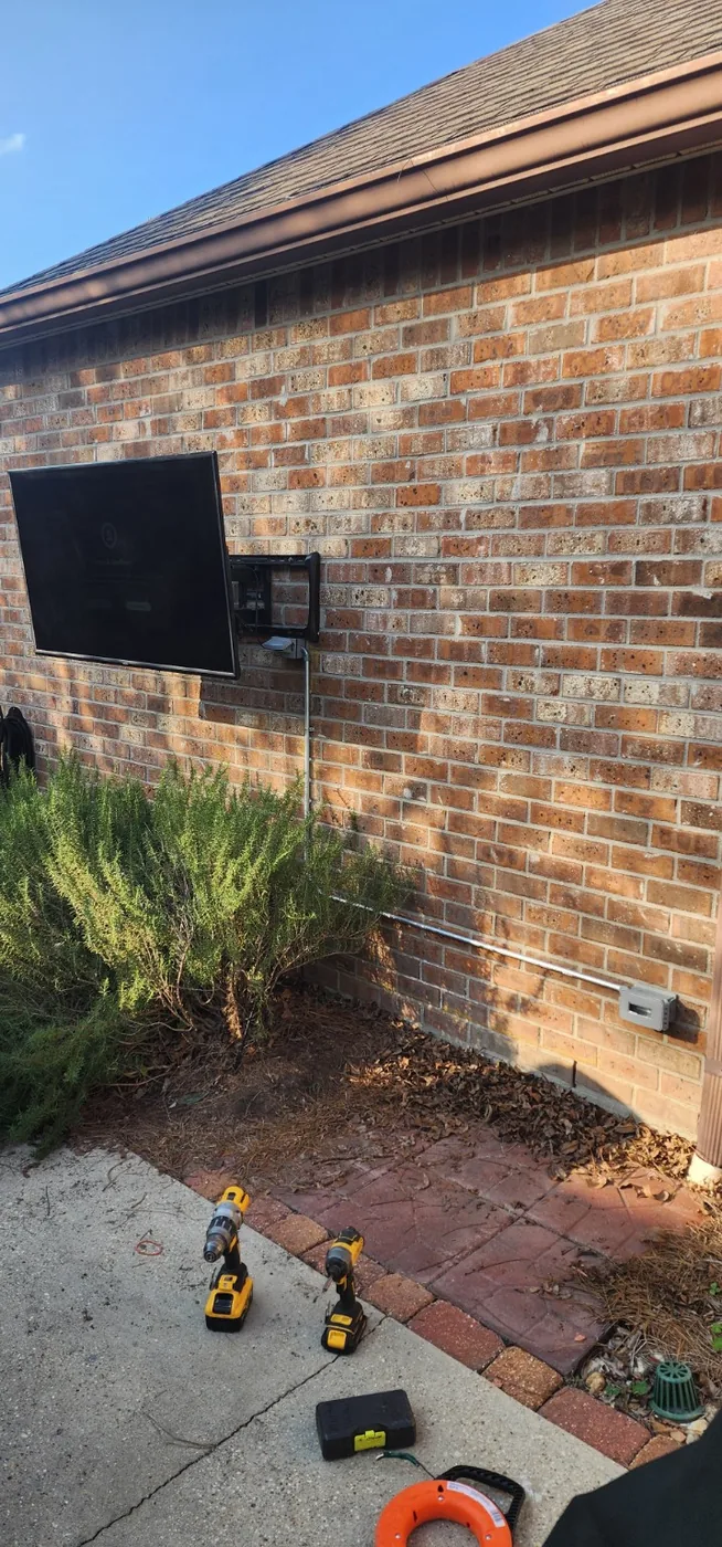 TV mounting installation on an exterior brick wall